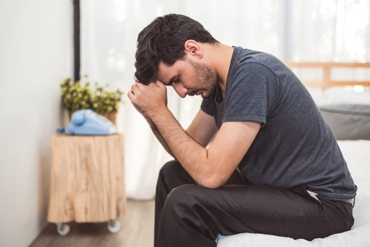 Stressed man sitting on bed