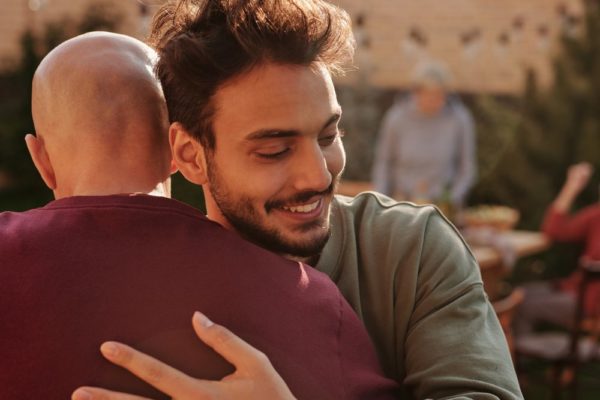 man in long sleeve shirt hugging a family member