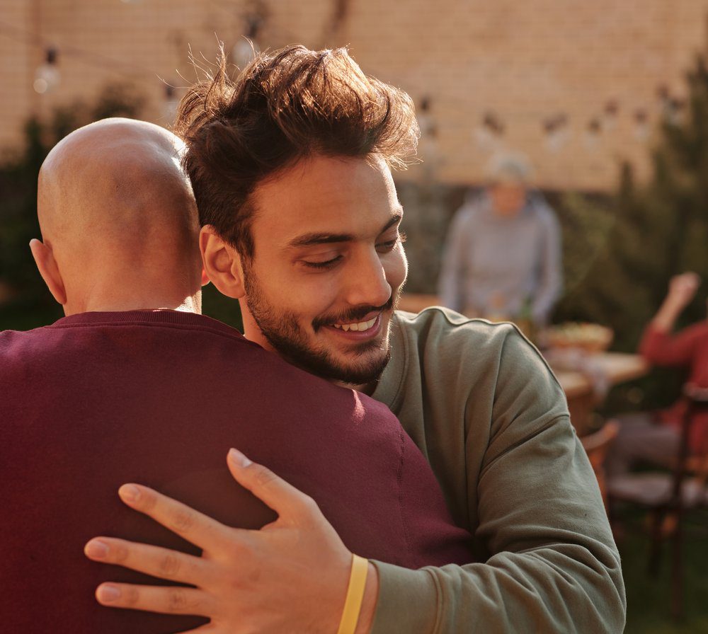 man in long sleeve shirt hugging a family member