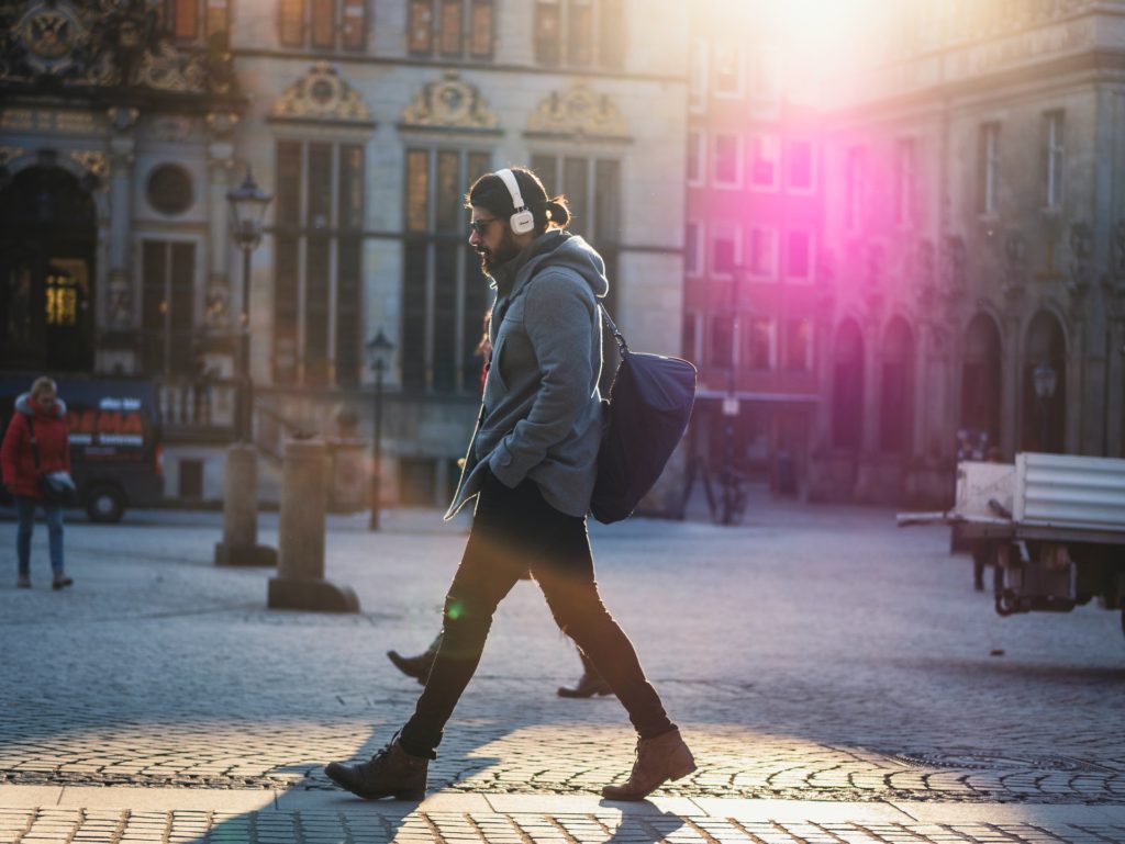 man walking on the street with headsets on